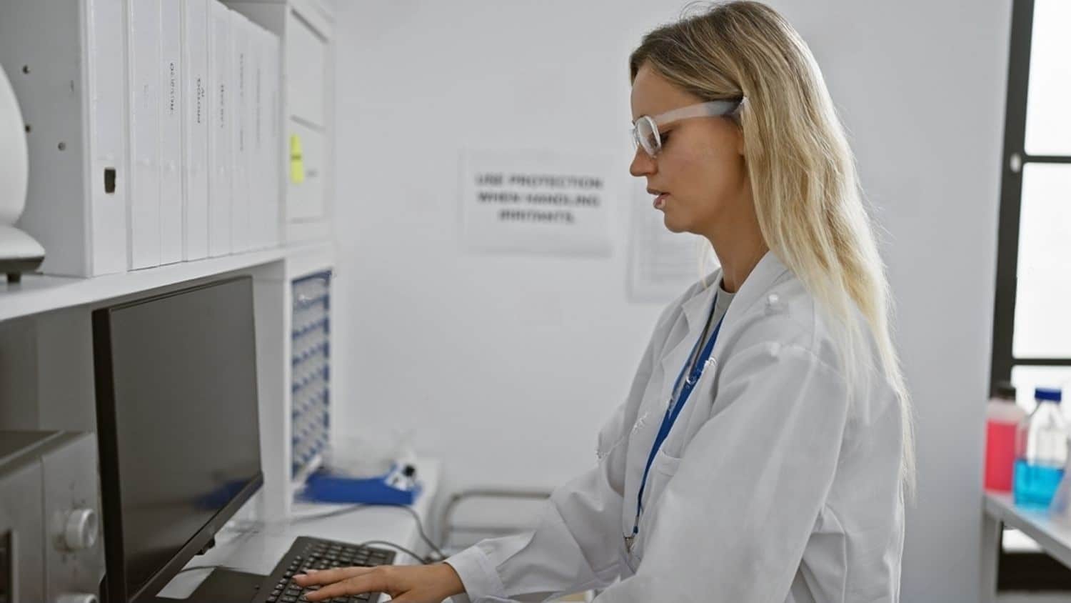 stock-photo-a-focused-blonde-woman-wearing-safety-glasses-works-on-a-computer-in-a-laboratory-setting-2458952993-transformed